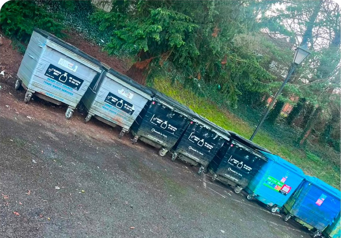 A row of large wheeled waste and recycling bins standing in a cleared bin store