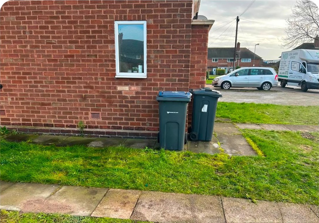 The same front lawn cleared, with only the wheelie bins left beside the house