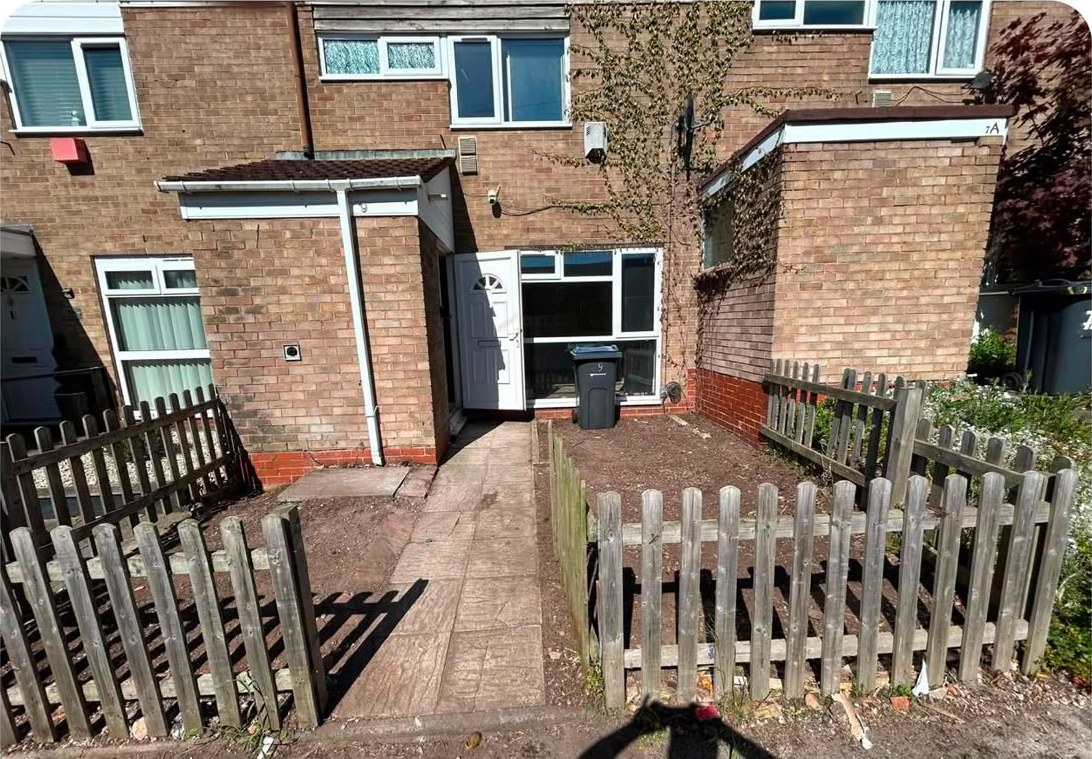 The same yard completely cleared, with the back of the house and a picket fence in view