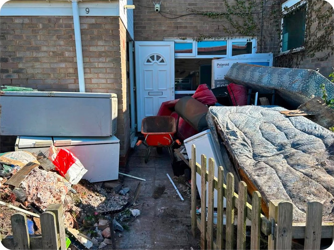 A yard piled with old fridge freezers, a mattress, rubble and broken furniture