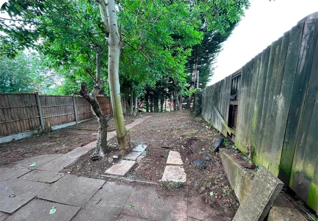 The same garden cleared back to bare ground, with the trees, fences and stepping stones in view